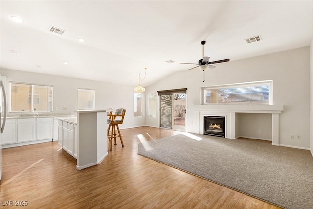 unfurnished living room featuring sink, vaulted ceiling, light hardwood / wood-style floors, and ceiling fan