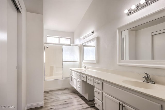 bathroom featuring hardwood / wood-style flooring, vanity, and combined bath / shower with glass door