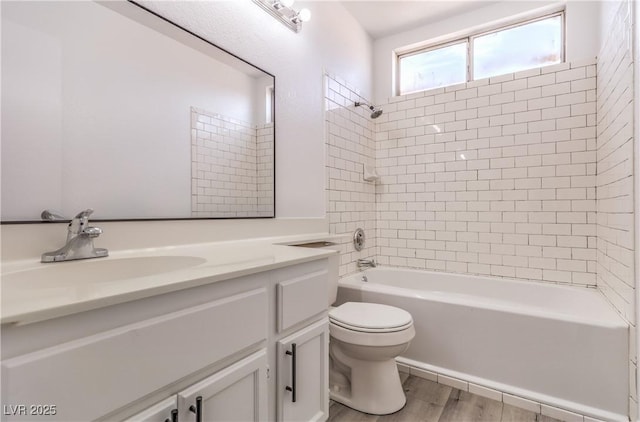 full bathroom featuring hardwood / wood-style flooring, vanity, toilet, and tiled shower / bath combo