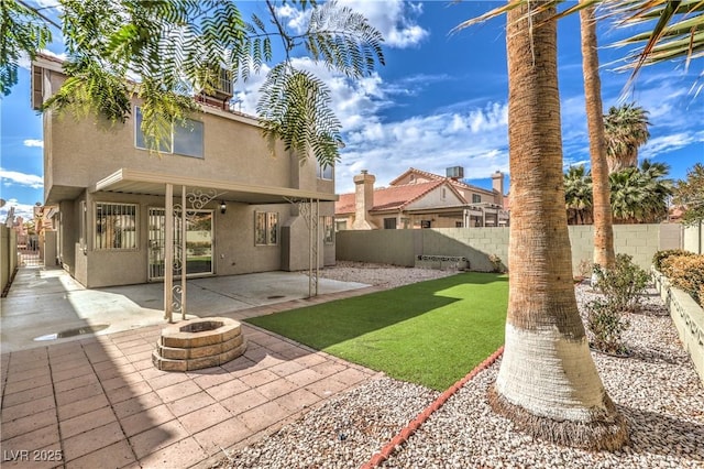 rear view of property featuring a lawn, a patio area, and a fire pit