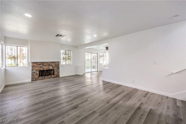 unfurnished living room with ceiling fan, a fireplace, and light hardwood / wood-style floors