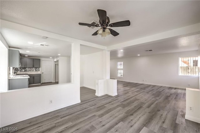 unfurnished living room with hardwood / wood-style floors, sink, and ceiling fan