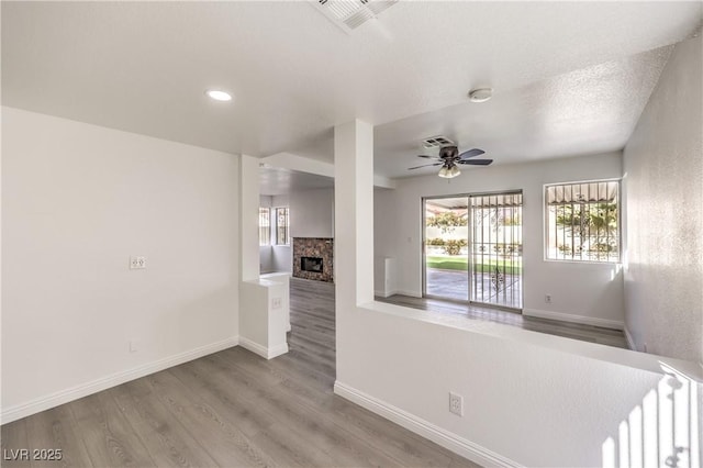 spare room featuring hardwood / wood-style flooring, ceiling fan, radiator heating unit, a fireplace, and a textured ceiling