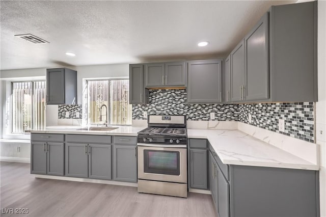 kitchen featuring sink, gray cabinetry, light wood-type flooring, and stainless steel gas stove