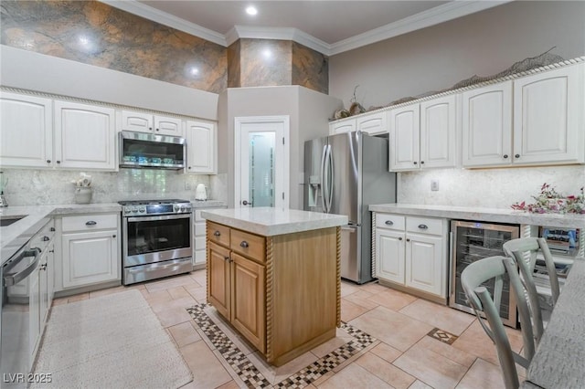 kitchen with stainless steel appliances, white cabinetry, a center island, and beverage cooler