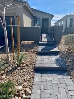 view of property exterior with a gate, fence, and stucco siding