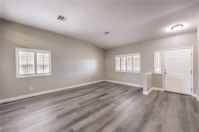 empty room featuring wood-type flooring and lofted ceiling