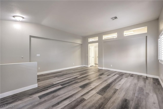 spare room with wood-type flooring and vaulted ceiling