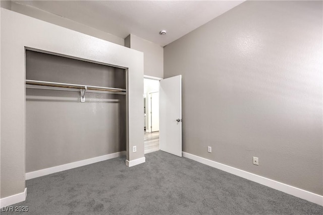 unfurnished bedroom with dark colored carpet and a closet