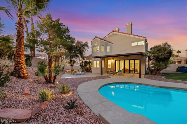 pool at dusk featuring an outdoor hangout area and a patio