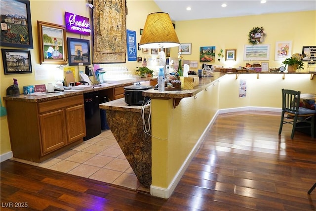 bar with black dishwasher and light wood-type flooring