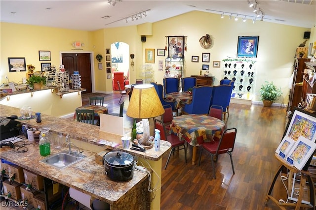 interior space with dark wood-type flooring, lofted ceiling, rail lighting, and sink