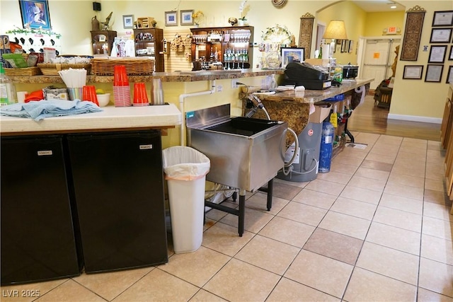 interior space featuring light tile patterned floors and a kitchen bar