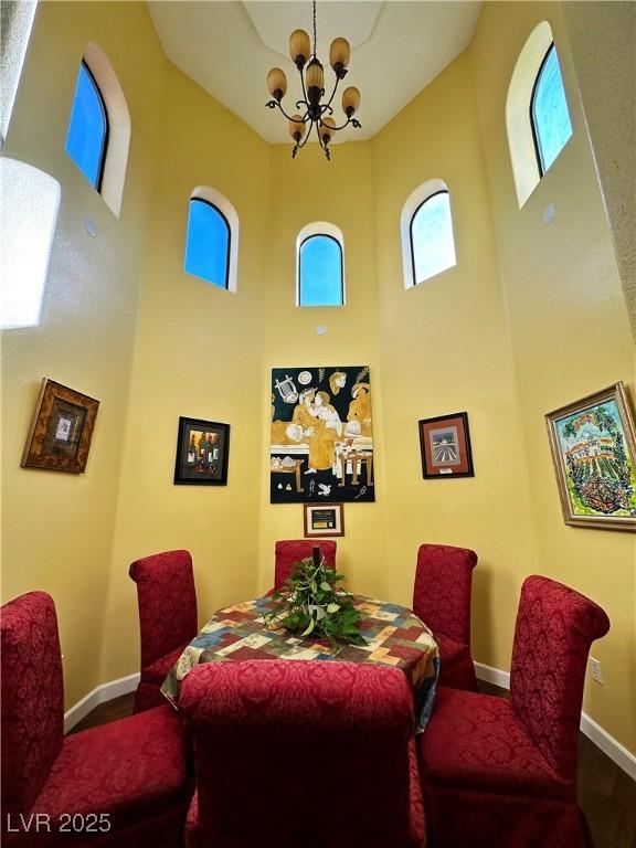 dining space with an inviting chandelier, wood-type flooring, and a high ceiling