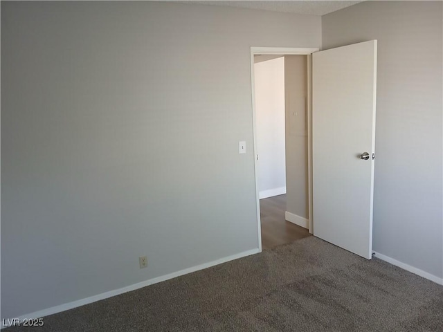 unfurnished room with dark colored carpet and baseboards