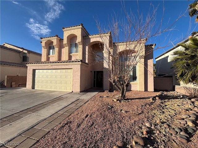 view of front of property with driveway, a tiled roof, an attached garage, and stucco siding