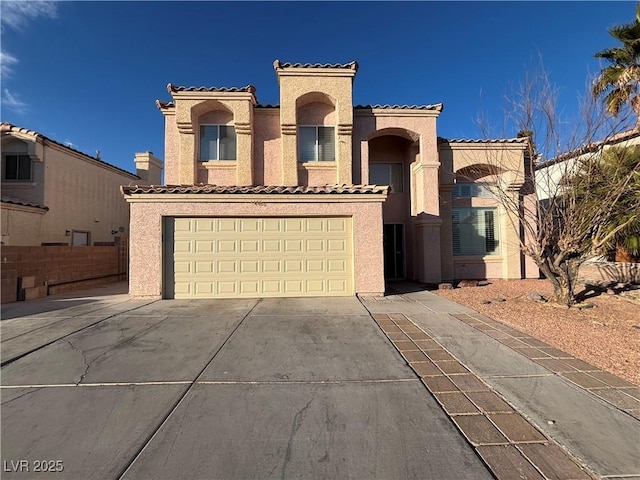 mediterranean / spanish-style home with a garage, concrete driveway, a tile roof, fence, and stucco siding