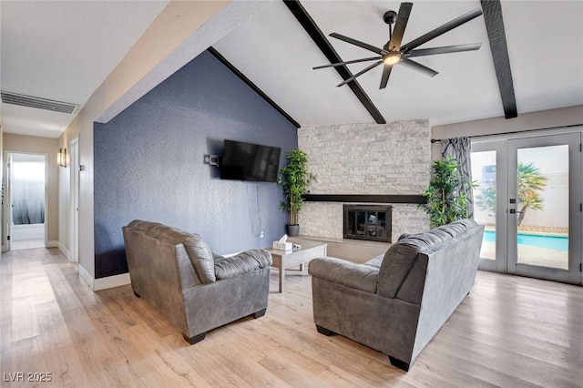 living room with a fireplace, vaulted ceiling with beams, ceiling fan, light wood-type flooring, and french doors