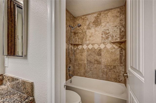 bathroom with toilet and tiled shower / bath