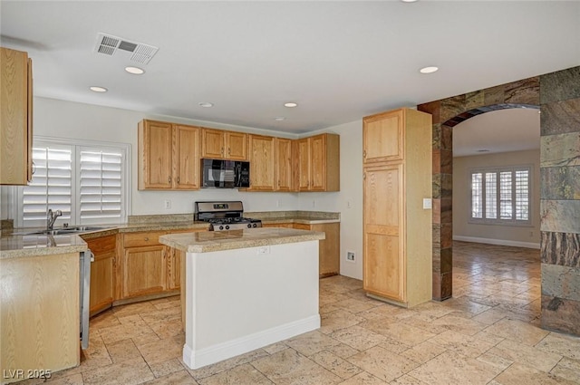 kitchen featuring light stone counters, sink, stainless steel range oven, and a kitchen island