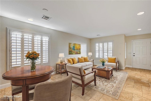 living room featuring baseboards, visible vents, stone tile floors, and recessed lighting