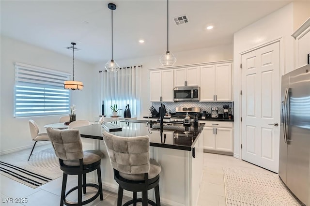 kitchen with hanging light fixtures, a kitchen bar, white cabinets, and appliances with stainless steel finishes