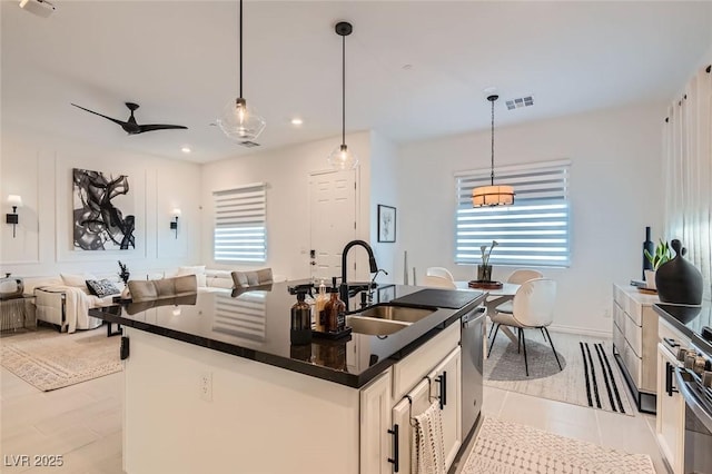 kitchen featuring pendant lighting, white cabinetry, an island with sink, and sink