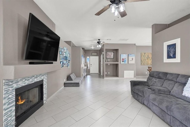 living room with light tile patterned flooring, ceiling fan, and a tiled fireplace