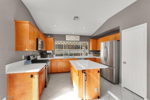 kitchen with sink, light tile patterned floors, stainless steel appliances, a center island, and vaulted ceiling