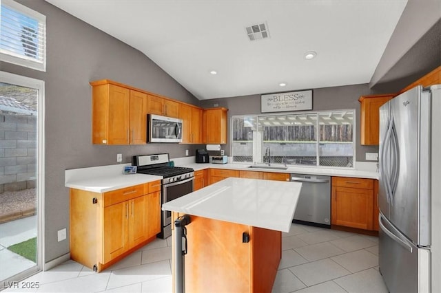 kitchen featuring lofted ceiling, sink, a center island, light tile patterned floors, and stainless steel appliances