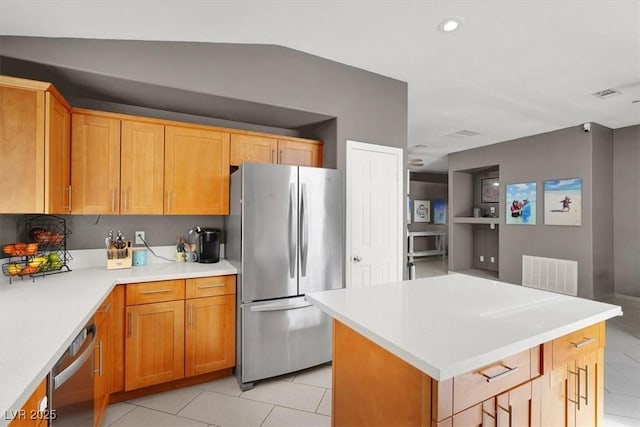 kitchen with stainless steel appliances, vaulted ceiling, a kitchen island, and light tile patterned floors