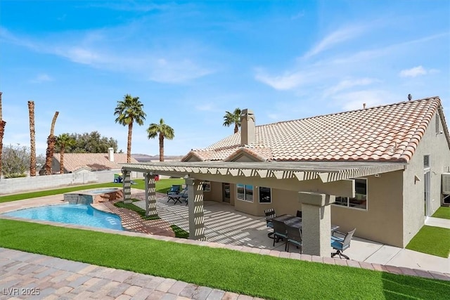 rear view of property with an in ground hot tub and a patio