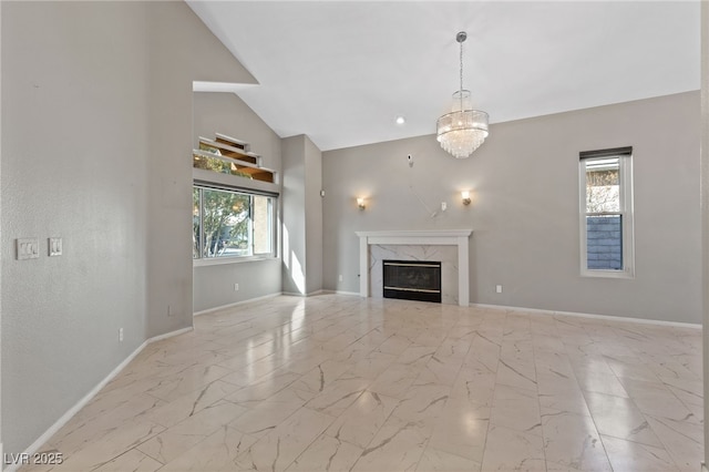 unfurnished living room featuring a high end fireplace, high vaulted ceiling, and a chandelier