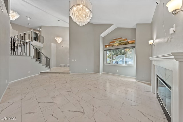 unfurnished living room featuring high vaulted ceiling, an inviting chandelier, and a high end fireplace