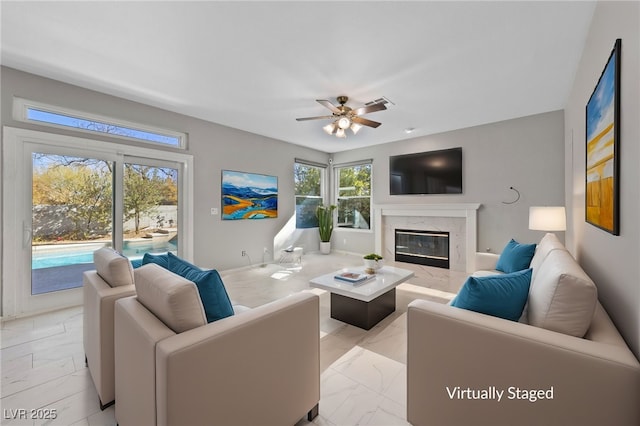 living room with a high end fireplace and ceiling fan