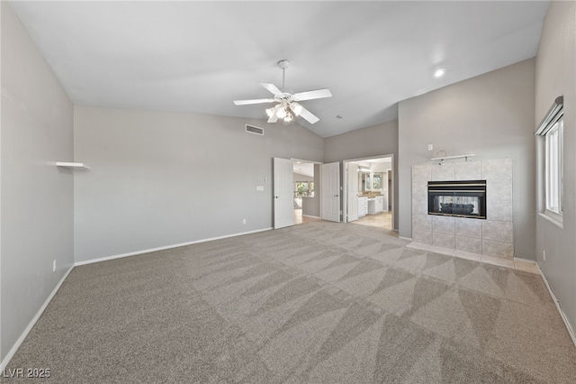 unfurnished living room featuring light carpet, a fireplace, lofted ceiling, and plenty of natural light