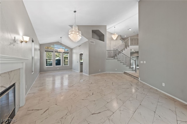 unfurnished living room featuring an inviting chandelier, a high end fireplace, and high vaulted ceiling