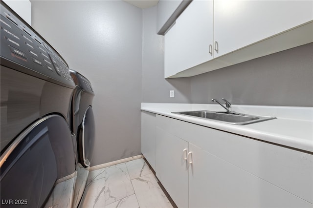 clothes washing area featuring cabinets, sink, and washer and dryer