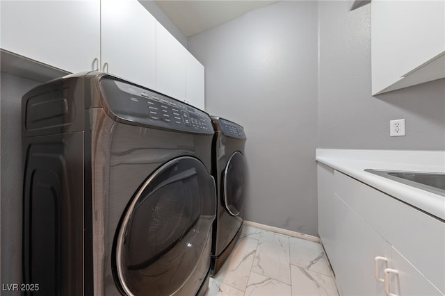 clothes washing area with sink, washing machine and dryer, and cabinets