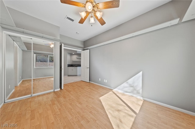 unfurnished bedroom with ceiling fan, light hardwood / wood-style flooring, and two closets