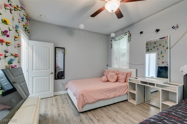 bedroom with a ceiling fan, wood finished floors, and baseboards