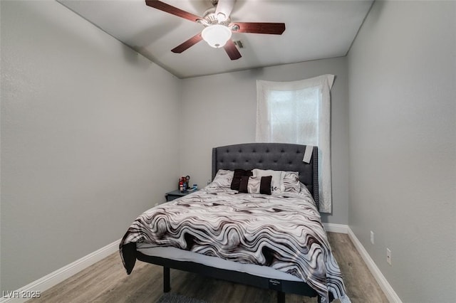 bedroom with a ceiling fan, wood finished floors, and baseboards