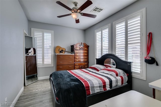 bedroom featuring visible vents, light wood-style flooring, a ceiling fan, and baseboards