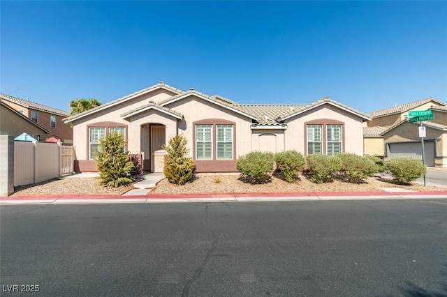 view of front of home featuring stucco siding, a tile roof, and fence