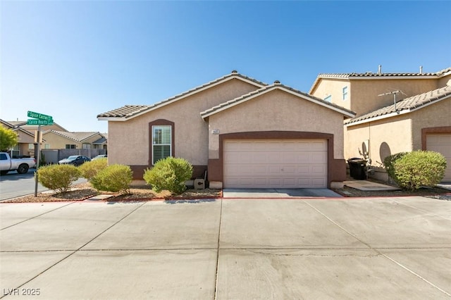 view of front of home featuring concrete driveway, a tiled roof, a garage, and stucco siding