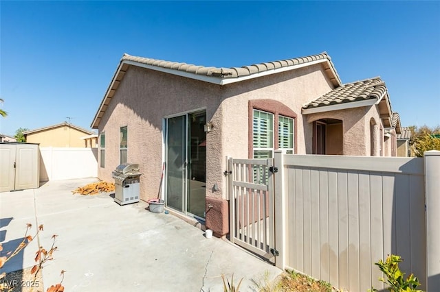 exterior space featuring a patio area, fence private yard, stucco siding, and a gate