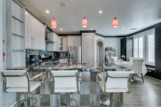 kitchen with visible vents, light wood-type flooring, a peninsula, appliances with stainless steel finishes, and tasteful backsplash