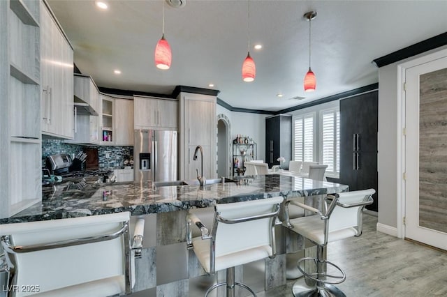 kitchen featuring a breakfast bar area, a peninsula, light wood-style floors, arched walkways, and stainless steel appliances