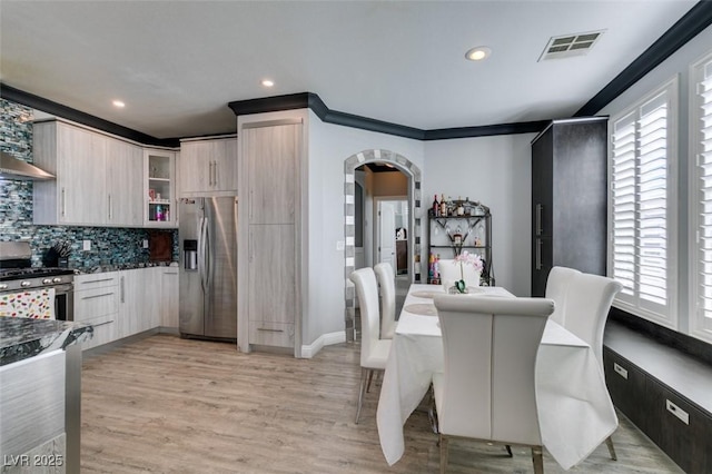 dining area with visible vents, light wood finished floors, recessed lighting, arched walkways, and crown molding