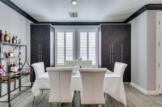 dining space featuring wood finished floors, visible vents, and baseboards